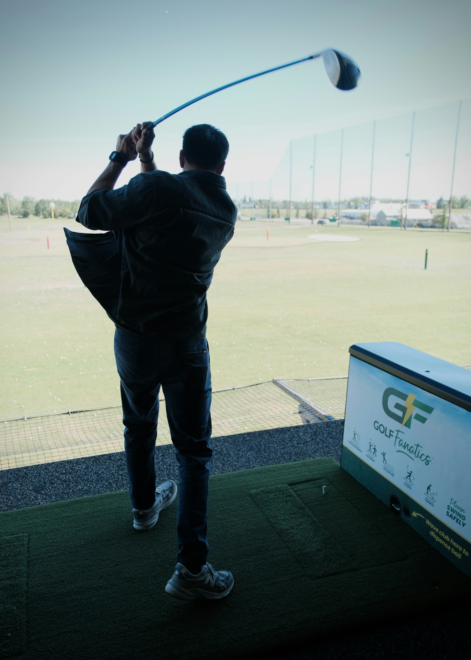 A player mid-swing in a floodlit bay at North 18